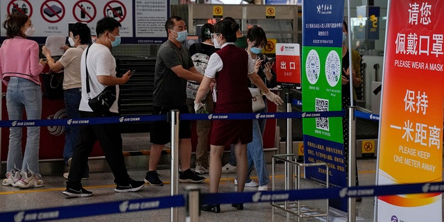 An airliner worker asks traveler to declare their health information after checking in at the international flight check in counter at the Beijing Capital International Airport in Beijing, Aug. 24, 2022. 