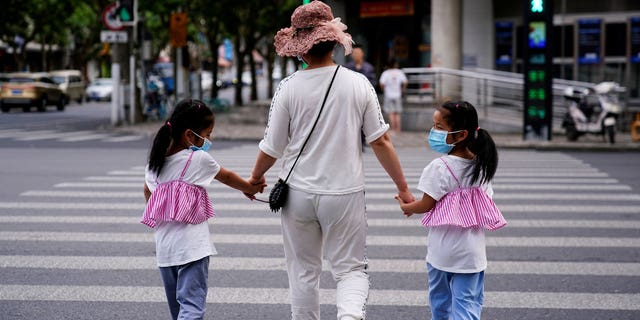 A mother walks with her twin daughters on a street in Shanghai, China, on June 7, 2021.