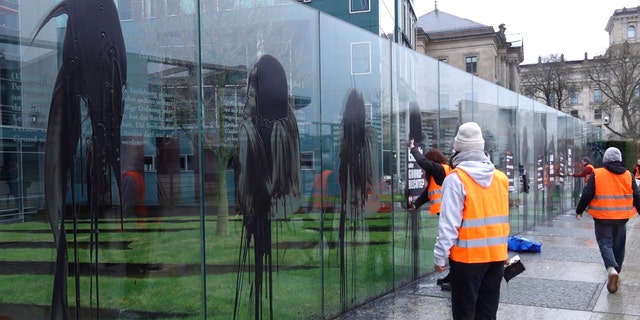 Climate activists of the "Last Generation" attend a protest at the Jakob-Kaiser-Building in Berlin, Germany, Saturday, March 4, 2023. Climate activists on Saturday splashed a dark liquid over an artwork near the German parliament building engraved with key articles from the country's constitution, drawing condemnation from the speaker of parliament and other lawmakers.