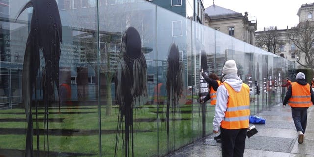 Climate activists of the "Last Generation" attend a protest at the Jakob-Kaiser-Building in Berlin Saturday, March 4, 2023. Climate activists on Saturday splashed a dark liquid over an artwork near the German parliament building engraved with key articles from the country's constitution, drawing condemnation from the speaker of parliament and other lawmakers.