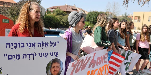 People hold placards as they mourn Elan Ganeles, a dual U.S.-Israeli citizen killed in a terrorist attack while he was driving near the West Bank city of Jericho by suspected terrorists, during his funeral, outside the cemetery, in Raanana, Israel, March 1, 2023. REUTERS/Nir Elias