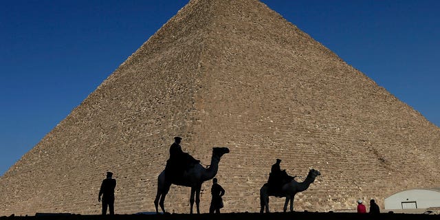 Policemen are silhouetted against the Great Pyramid of Giza, Egypt, on Dec 12, 2012. Egypt unveiled on March 2, 2023, the discovery of a 30-foot-long chamber inside the pyramid.