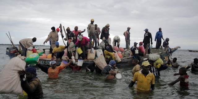 Fishermen swim out from an incoming boat at a berth, some with their overnight catch in Kwale county, Gazi Bay, Kenya, on June 12, 2022.