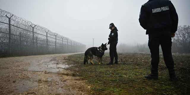 Bulgarian border police officers patrol with a dog in front of the border fence on the Bulgaria-Turkey border on Jan. 13, 2023. The anti-torture monitor in Europe decried border guards use of violence and dogs to humiliate migrants.