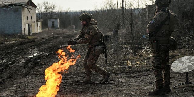 Ukrainian servicemen light a fire with gunpowder to get warm near the city of Bakhmut in the region of Donbas on March 5, 2023.