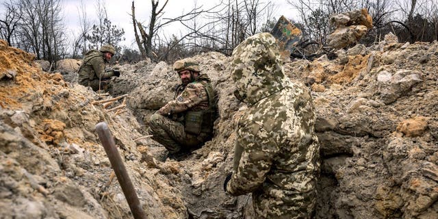 Ukrainian infantrymen take cover in a partially dug trench along the front line on March 5, 2023, outside of Bakhmut, Ukraine.