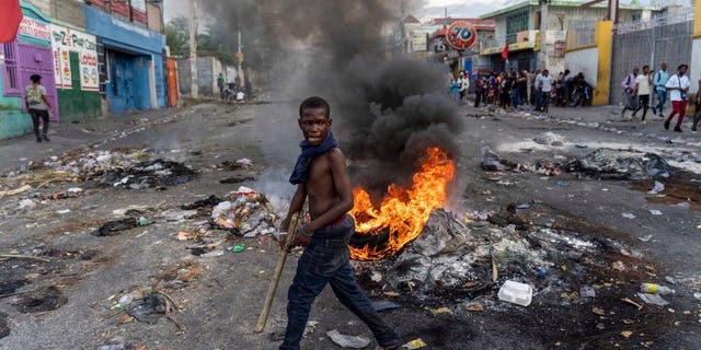 A man walks past a burning barricade during a protest against Haitian Prime Minister Ariel Henry calling for his resignation, in Port-au-Prince, Haiti, October 10, 2022.