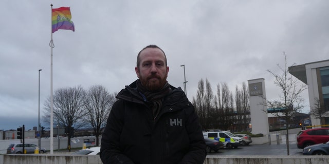 Dave McConnell outside the Elland Road Police Station where he was detained, which flies an LGBTQ flag.