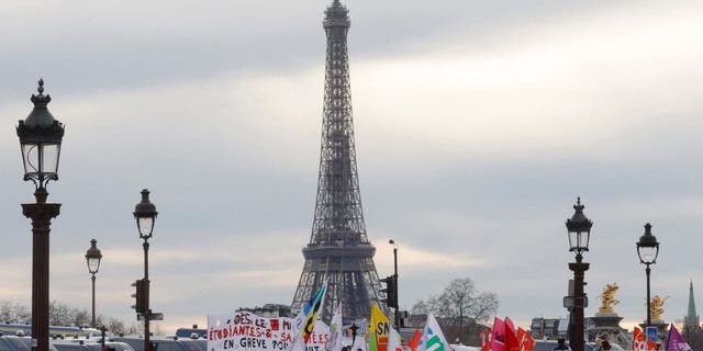 Demonstrators holds banners as they gather on the place de la Concorde near the National Assembly, with the Eiffel tower in the background, to protest after French Prime Minister Elisabeth Borne delivered a speech to announce the use of the article 49.3, a special clause in the French Constitution, to push the pensions reform bill through the lower house of parliament without a vote by lawmakers, in Paris, France, March 16, 2023.   
