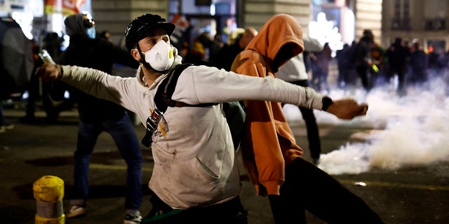 A demonstrator trows a projectile amid clashes during a protest after French Prime Minister Elisabeth Borne used the article 49.3, a special clause in the French Constitution, to push the pensions reform bill through the National Assembly without a vote by lawmakers, in Nantes, France, March 16, 2023.  