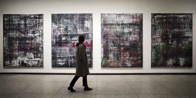 A woman walks in front of the Birkenau paintings in a new exhibition of art works created by Gerhard Richter at the Neue Nationalgalerie museum in Berlin, Germany, on March 31, 2023. 