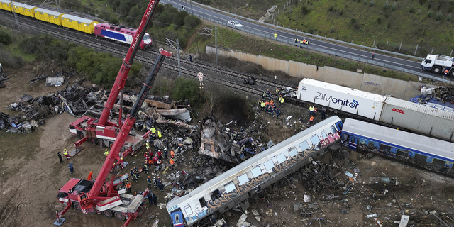 Firefighters and rescuers, supported by two cranes, search through the wreckage in Tempe on Thursday following the train collision.