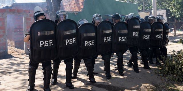 Police in riot gear stand at the ready after the burial of Máximo Jerez, an 11-year-old boy killed in the crossfire of a drive-by shooting in the Los Pumitas neighborhood of Rosario, Argentina, on March 6, 2023.