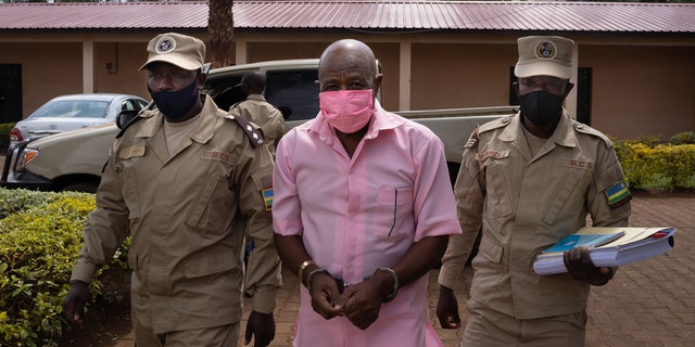 "Hotel Rwanda" hero Paul Rusesabagina (C) in the pink inmate's uniform arriving at Nyarugenge Court of Justice in Kigali, Rwanda, on Oct. 2, 2020, surrounded by guards of Rwanda Correctional Service (RCS).
