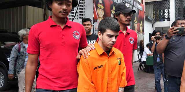 Police officers escort Brazilian national Gustavo Pinto da Silveira prior to a press conference in Jakarta, Indonesia, on March 15, 2023. Indonesian authorities arrested four foreigners who allegedly tried to smuggle drugs into the country.