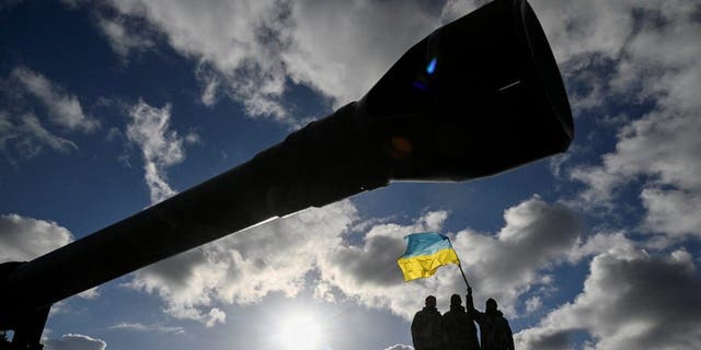 Ukrainian personnel hold a Ukrainian flag as they stand on a Challenger 2 tank during training at Bovington Camp, near Wool in southwestern Britain, Feb. 22, 2023.