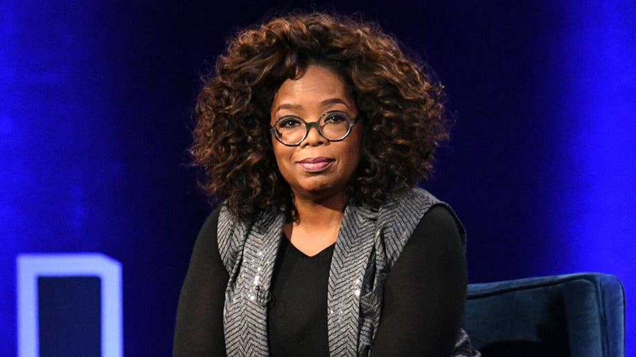 Oprah Winfrey wears black shirt and vest during panel discussion