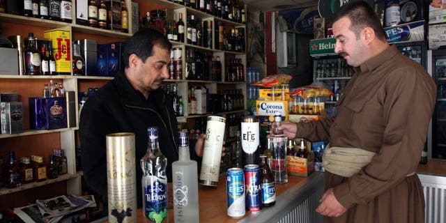 A shopkeeper displays a selection of Turkish alcoholic drinks to a Kurdish man at a store in Arbil, north of Baghdad, Dec. 8, 2010.