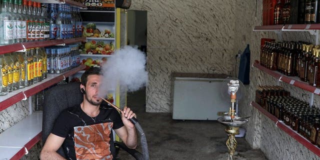 Steve Ibrahim, an alcohol shop owner, smokes in the town of Qaraqosh, south of Mosul, Iraq, April 13, 2017.