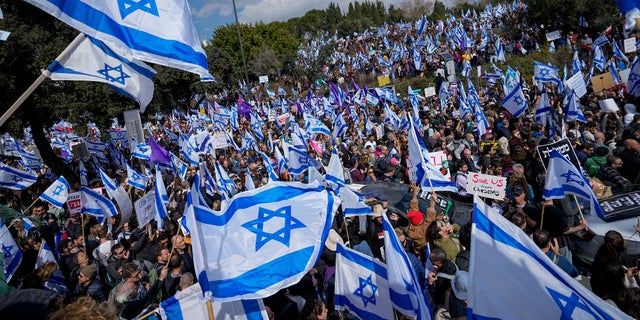 Israelis wave national flags during protest against plans by Prime Minister Benjamin Netanyahu's new government to overhaul the judicial system, outside the Knesset, Israel's parliament, in Jerusalem, Monday, Feb. 13, 2023. Thousands of Israelis protested outside the country's parliament on Monday ahead of a preliminary vote on a bill that would give politicians greater power over appointing judges, part of a judicial overhaul proposed by Prime Minister Benjamin Netanyahu's government.