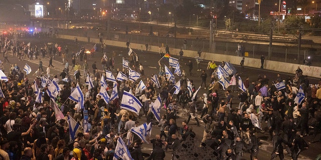 Israeli police disperse demonstrators blocking a highway during a protest against plans by Prime Minister Benjamin Netanyahu's government to overhaul the judicial system in Tel Aviv, Israel, Monday, March 27, 2023. 