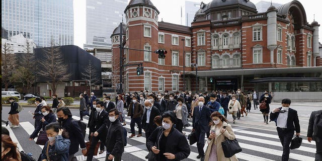 People walk across an intersection near Tokyo Station on March 13, 2023. Japan dropped its masking request Monday for the first time in three years as the country further eases COVID-19 rules in public places. 