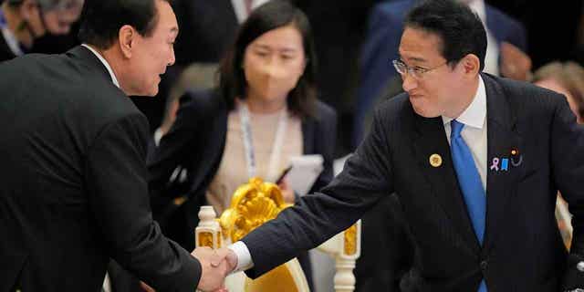 Japan's Prime Minister Fumio Kishida, right, shakes hands with South Korea's President Yoon Suk Yeol in Cambodia, on Nov. 13, 2022. The leaders of the two countries will hold a summit next week, 