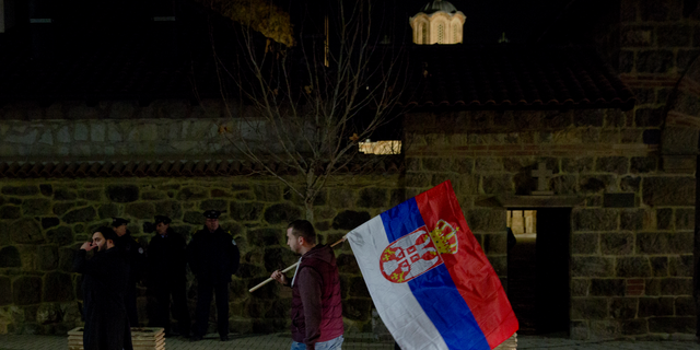 A protester carries a Serb flag and joins a demonstration against Serbian President Aleksandar Vucic in the town of Gracanica, Kosovo, on Feb. 9, 2019. (AP Photo/Visar Kryeziu)