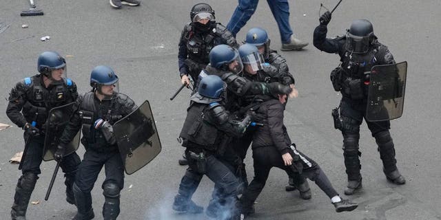 Riot police scuffle with a protester during a rally in Paris, Thursday, March 23, 2023. French unions are holding their first mass demonstrations since President Emmanuel Macron enflamed public anger by forcing a higher retirement age through parliament without a vote.
