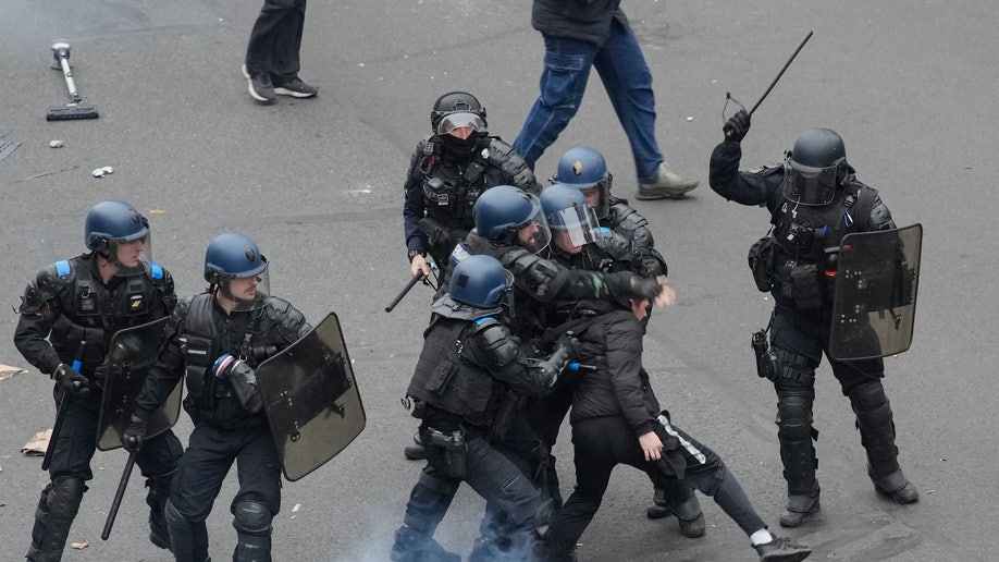 Riot police scuffle with a protester during a rally in Paris