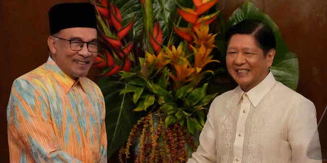 Philippine's president, right, shakes hands with Malaysia's prime minister after delivering their statements to the press in Manila, Philippines, on Mar. 1, 2023. Malaysia's prime minister claims over 200,000 migrants have entered his country from Burma.