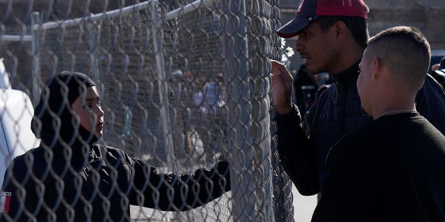 Migrants, right, as a member of the Mexican National Guard if there is any new information available regarding the victims of a fire at an immigration detention center that killed dozens, in Ciudad Juarez, Mexico, Tuesday, March 28, 2023.