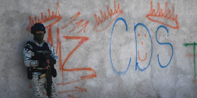 A Mexican soldier stands guard next to some graffitis of the drug trafficker Mayo Zambada (MZ) and the criminal group "Cartel de Sinaloa" (CDS), in Palmas Altas village, Jerez de Garcia Salinas municipality, Zacatecas state, Mexico, on March 14, 2022. 
