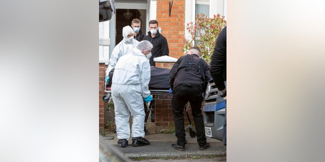 Police remove what appears to be human remains after exhuming them from a shallow backyard grave.