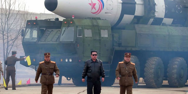 North Korean leader Kim Jong Un, center, walks around a Hwasong-17 intercontinental ballistic missile on the launcher at an undisclosed location in North Korea.