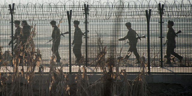 FILE: North Korean soldiers patrol next to the border fence near the town of Sinuiju across from the Chinese border town of Dandong. 
