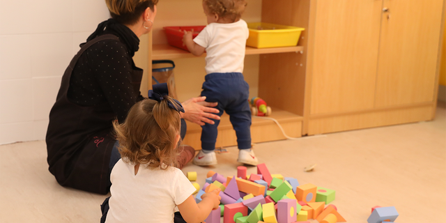 Children play in a classroom with teacher.