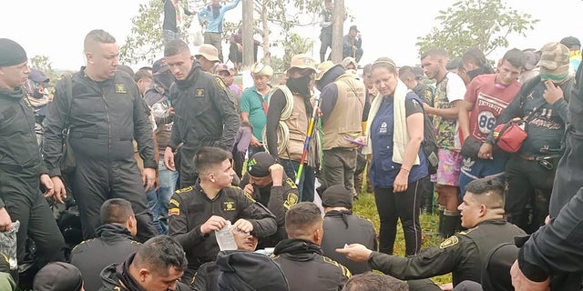 Police sit while officials from Colombia's human rights ombudsman speak with demonstrators who, according to authorities, belong to rural and Indigenous communities and are demanding that oil company Emerald Energy build roads in San Vicente del Caguan, Colombia, March 2, 2023. 