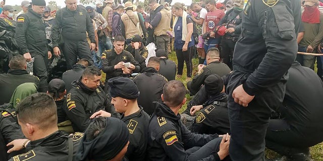 Police sit near officials from Colombia's human rights ombudsman while they speak with demonstrators in San Vicente del Caguan, Colombia, March 2, 2023. 