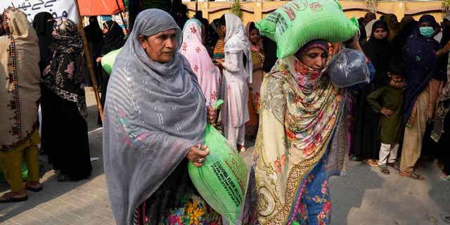 Women leave while others wait their turn to get a free sack of wheat flour at a distribution point in Lahore, Pakistan, on March 30, 2023. The country's government is providing flour to poor families during Ramadan due to high inflation in the country. 