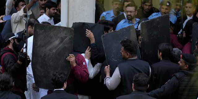 Security personnel with bulletproof shields escort former Prime Minister Imran Khan, center, as he arrives at a courthouse in Islamabad, Pakistan, on March 27, 2023. A Pakistani court ruled in defense of Khan on Monday.