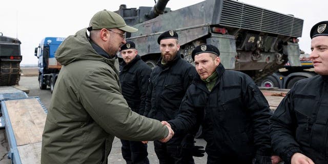 Ukrainian Prime Minister Denys Shmyhal greets Polish service members delivering Leopard 2 tanks on the first anniversary of Russia's attack, in Ukraine on Feb. 24, 2023.