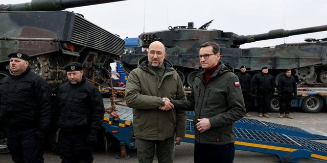 Ukrainian Prime Minister Denys Shmyhal and Polish Prime Minister Mateusz Morawiecki shake hands during the delivery of tanks to Ukraine, Feb. 24, 2023.