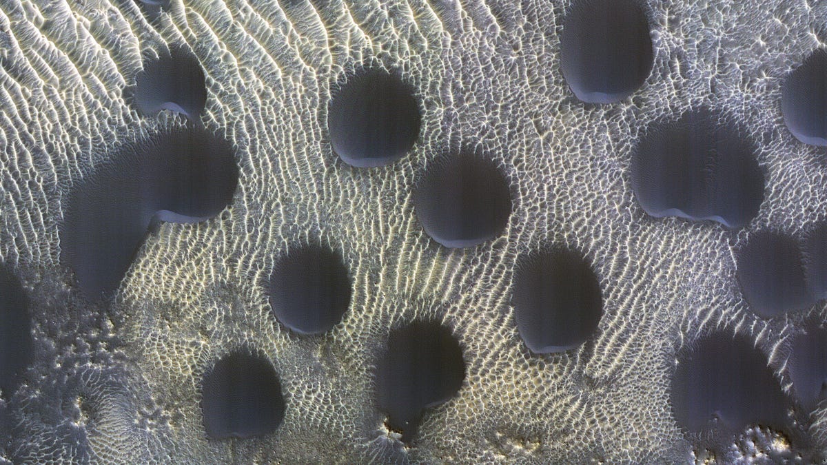 Processed NASA MRO view of dark-looking sand dunes on Mars. Smaller, lighter ripples surround the dunes, some of which look like circular polka dots.