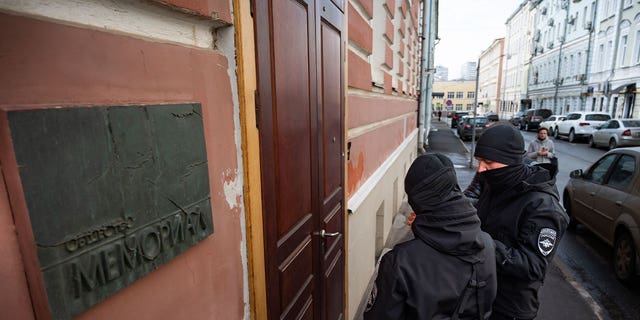 Two Russian police officers stand in front of the door of the Memorial office in Moscow, Russia, on March 21, 2023. Russian authorities raided homes and offices of human rights advocates and historians associated with the prominent rights group Memorial that won the Nobel Peace Prize last year. 