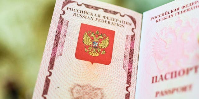 The emblem of the Russian Federation drawn in the passport. A woman shows her Russian passport.