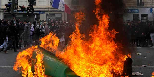 Demonstrators walk past burning garbage cans during a demonstration on March 28, 2023, in Paris. Sanitation workers in Paris will return to work on Wednesday as the protests seem to be calming down.