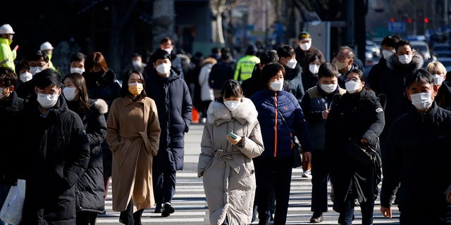 Commuters cross a street in Seoul, South Korea, on Feb. 3, 2021.