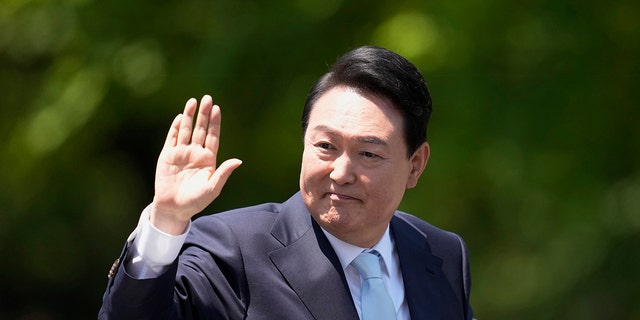 South Korea's new President Yoon Suk Yeol waves from a car after the Presidential Inauguration outside the National Assembly in Seoul, South Korea.