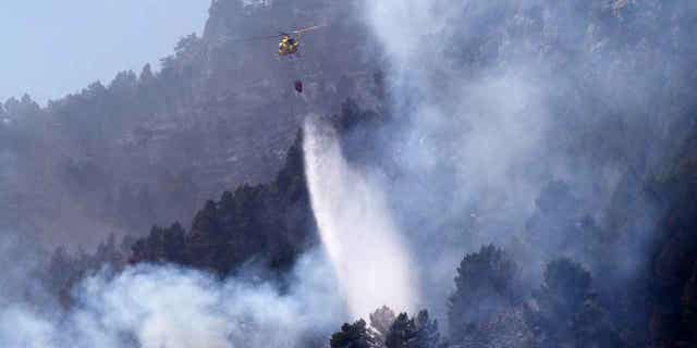 A helicopter drops water on a forest fire in Montanejos, Castellon de la Plana, Spain, on March 26, 2023. 